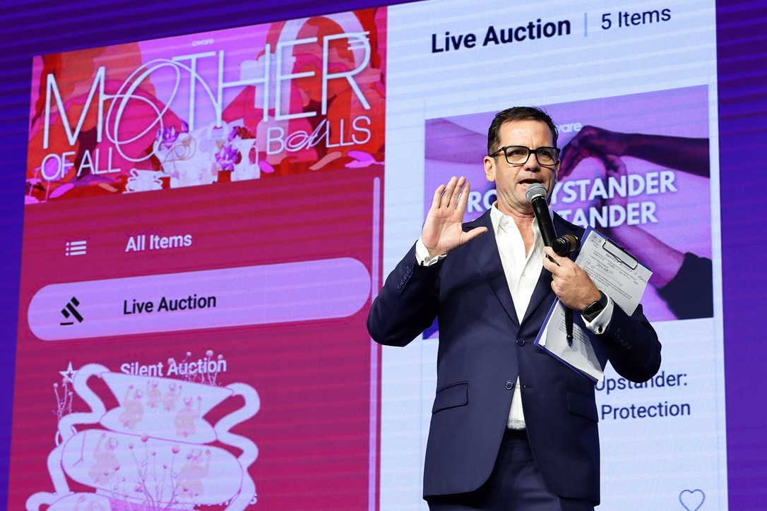 Shaun McEwan holding a gavel on stage during a live charity auction